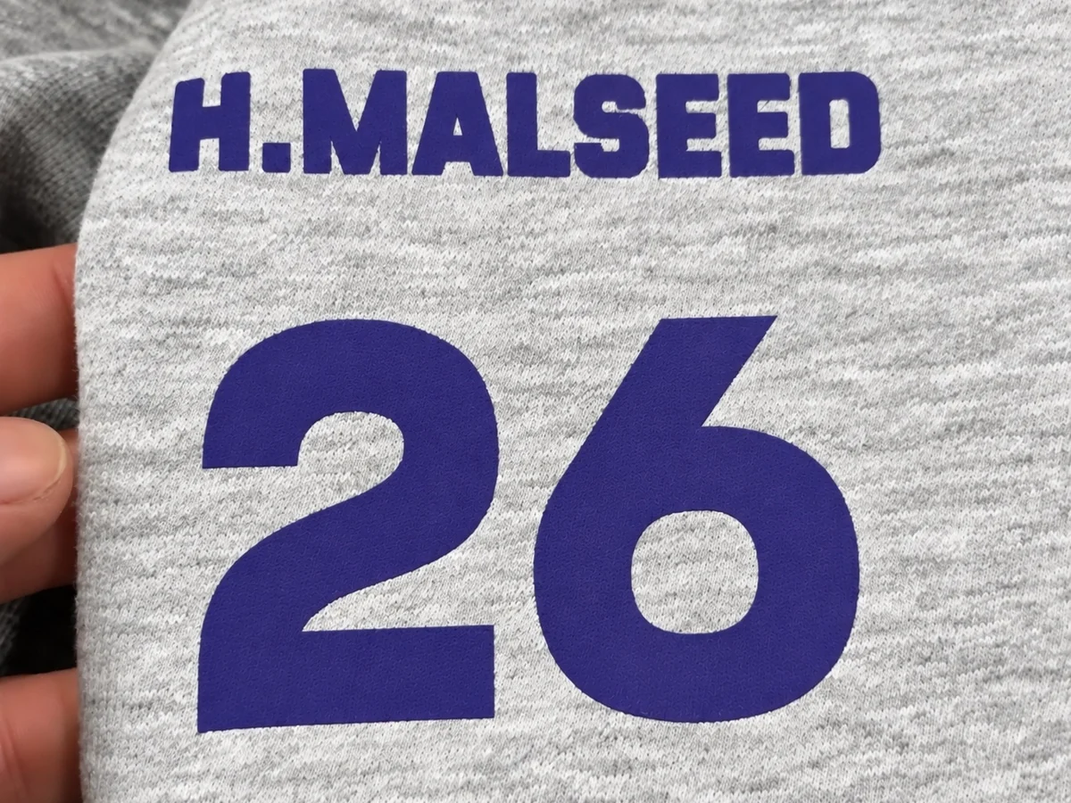 Name and number printed on the back of a gray shirt